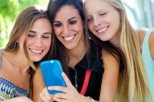 Outdoor portrait of group of friends having fun with smartphones.